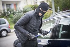 a thief looking around before breaking into a car