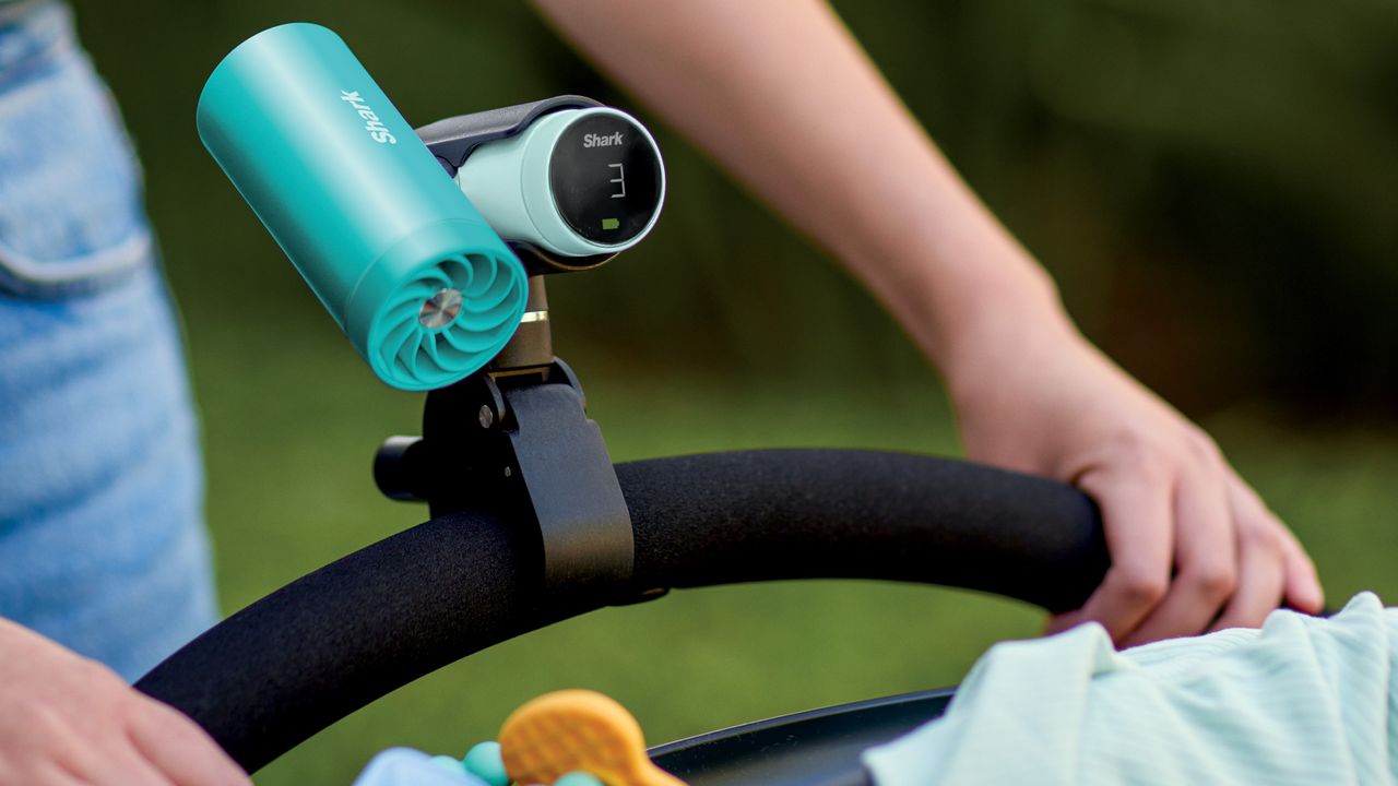 Person pushing stroller with Shark ChillPill personal misting fan attached to handle