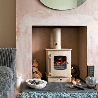 A plastered living room wall with a light pink wood burner fire