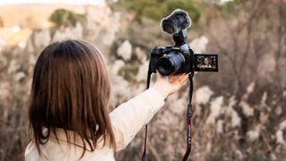 A person filming themselves using the Canon EOS R7 outdoors