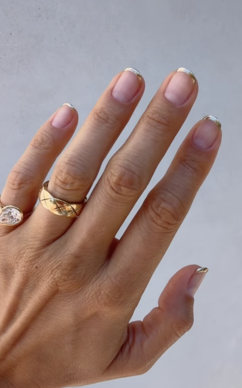 Short natural nails with ultra-thin metallic gold French tips and a glossy clear base