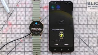 Samsung Galaxy Watch 7 next to a Samsung Galaxy S24 smartphone showing the start of the pairing process