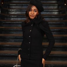 Ayo Edebiri wears a black two-piece with a black hat and high-vamp heels at Chanel's Métiers d'art Show in New York