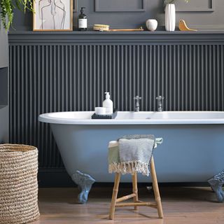 bathroom with grey wall and wooden floor and blue bathtub and side table