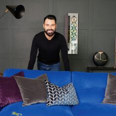 Rylan Clark in his living room standing behind his blue DFS sofa