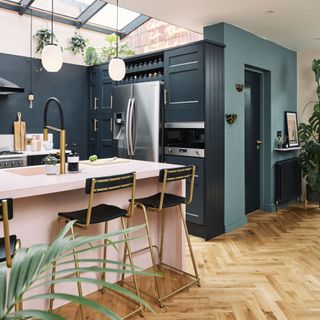 navy kitchen with parquet floor, pink island and large fridge