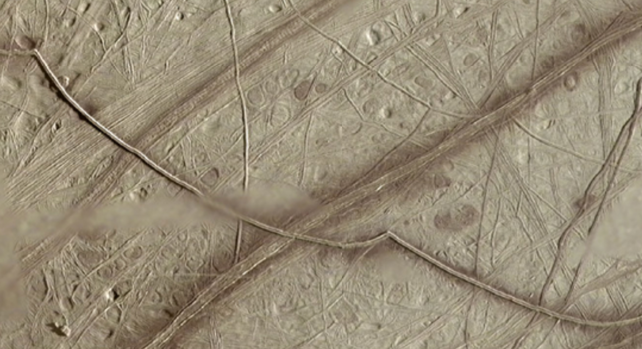 A screenshot from Europa Trek showing the many criss-crossing fracture bands on Europa's icy surface. The large, dark band stretching from the lower left to the top right is named Belus Linea.