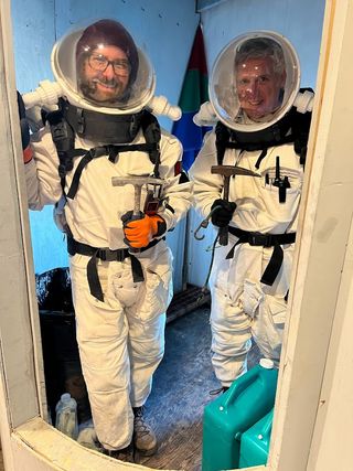 two people in space suits pose in a doorway