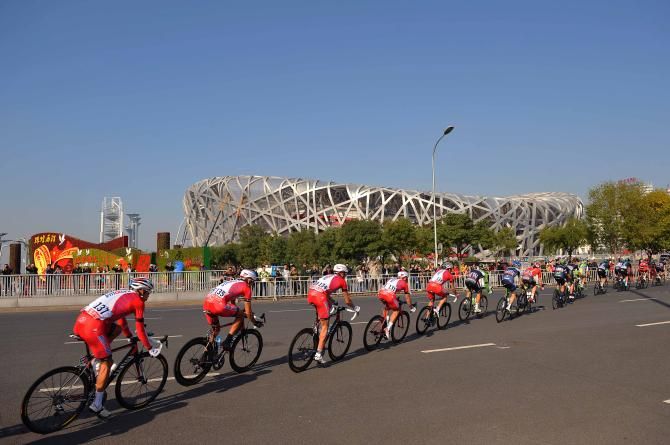 The peloton string out as the pass the Bird's Nest Stadium