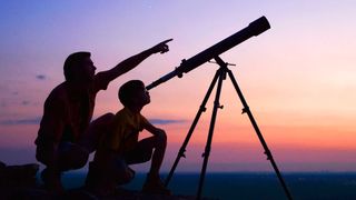 Two people using telescope to look at night sky