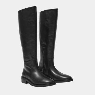 A cutout of flat riding boots from & Other Stories against a pale grey background