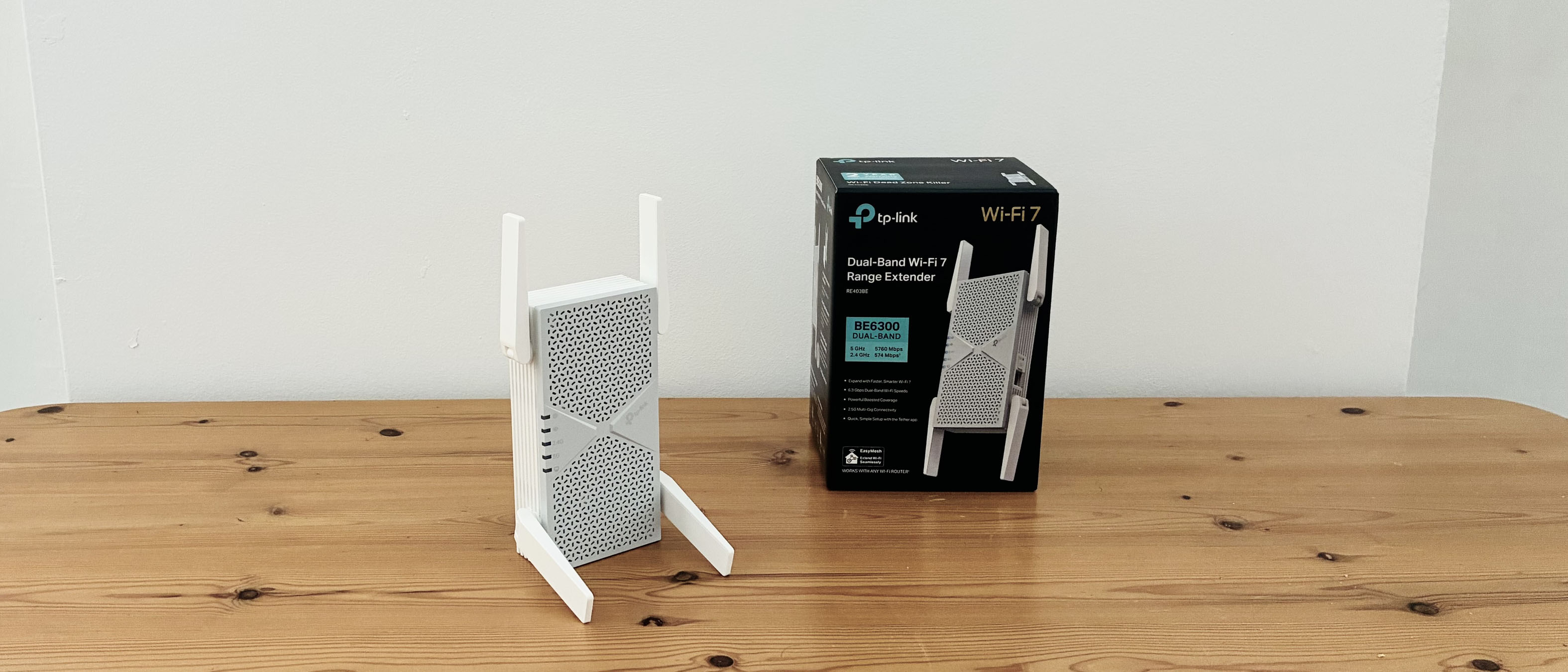 TP-Link BE6300 Wi-Fi extender on wooden desk