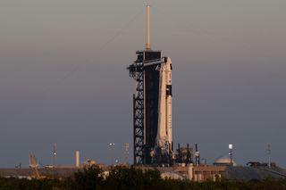 rocket beside a launch tower with gray sky behind