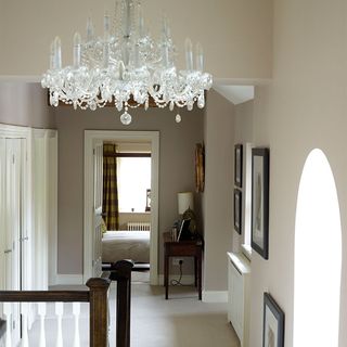 A neutral landing with a glass chandelier and three doors