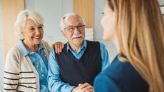 Senior couple talking with female financial advisor at her office.