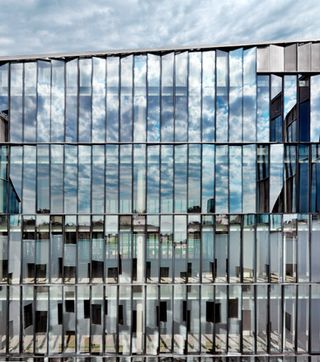 Mirrored glass panels are angled to reflect the building itself and the sky above