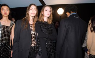 Models wear a range of black chainmail tops and dresses, layered with black blazers and denim shirts