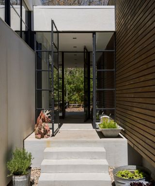 An example of how to decorate a front porch showing white stone steps leading to a stylish black doorway with glass panels
