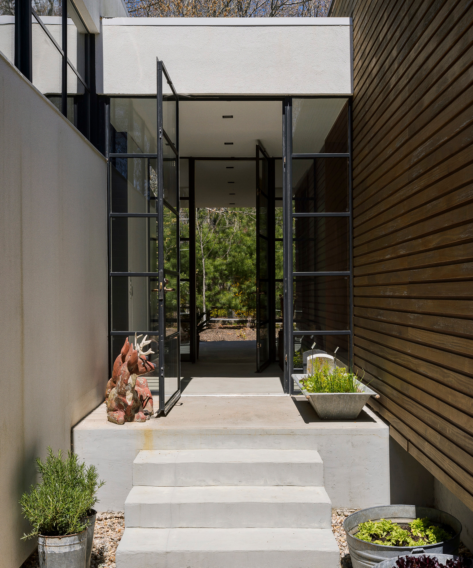 An example of how to decorate a front porch showing white stone steps leading to a stylish black doorway with glass panels