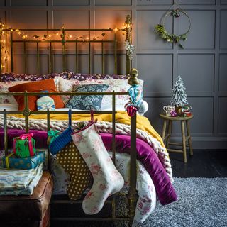 Navy bedroom dressed for Christmas with fairy lights and stocking on bed frame