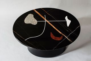 A round stone table by Virginia Gordon, featuring abstract shapes applied to the tabletop through a marquetry technique
