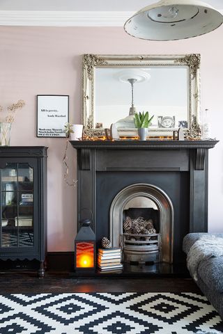 Elegant fireplace with large mirror and patterned rug on the floor