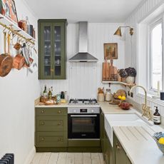 Small white L-shaped kitchen with wall panelling and green cabinetry