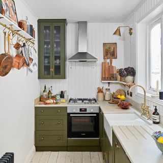 Small white L-shaped kitchen with wall panelling and green cabinetry