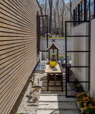 An example of small backyard ideas showing a small courtyard area with bird statues, pavers and a narrow table