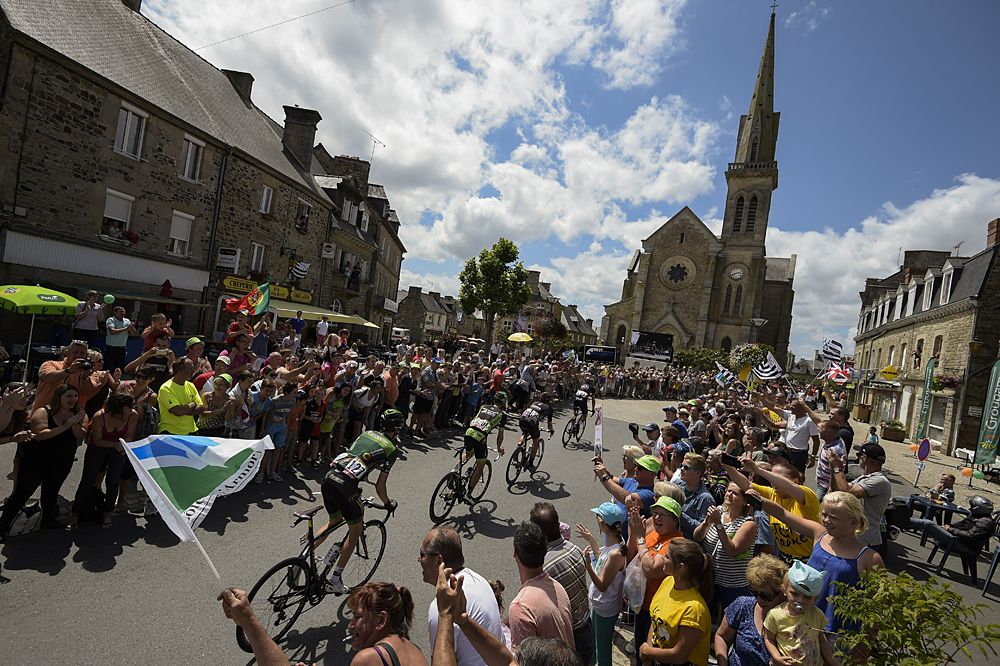Supporters cheer along the road as the pack rides during the 181.5 km eighth stage of the 102nd edition of the Tour de France