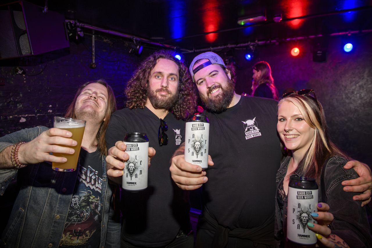 People drinking, smiling and throwing horns at the Metal Hammer 400 party