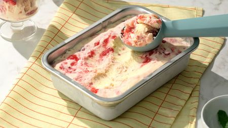 A small rectangular stainless steel food container filled with ice cream with a scoop on top 