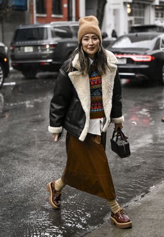 a woman at fashion week wearing an aviator jacket with sperry boat shoes