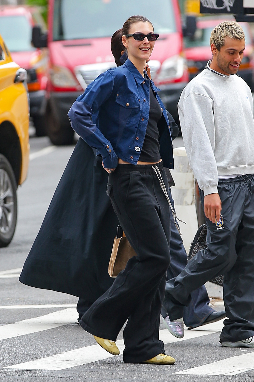 Vittoria Ceretti wearing a navy jacket and black T-shirt with black pull-on pants and butter yellow sneakers in NYC.