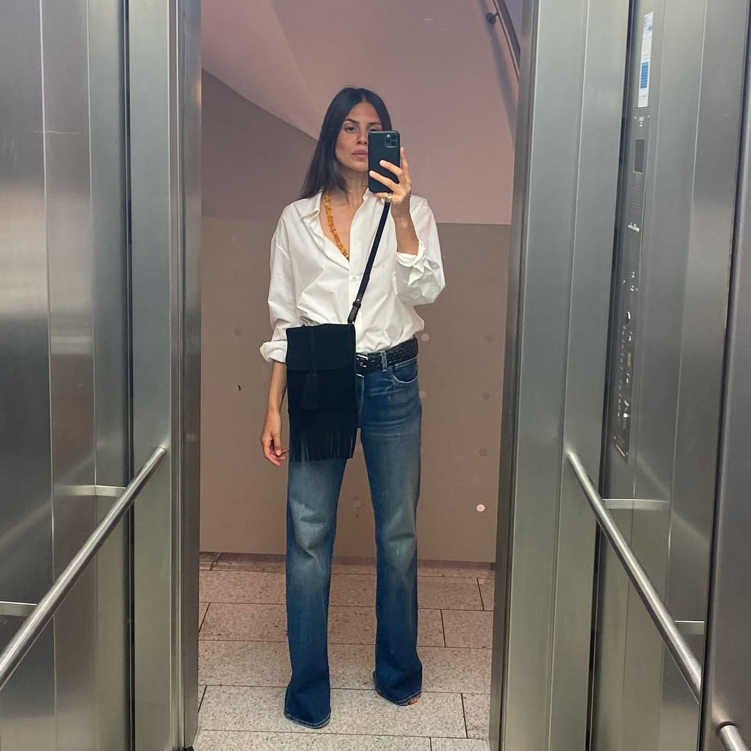 Woman wearing long, baggy jeans fall denim trend 2025.