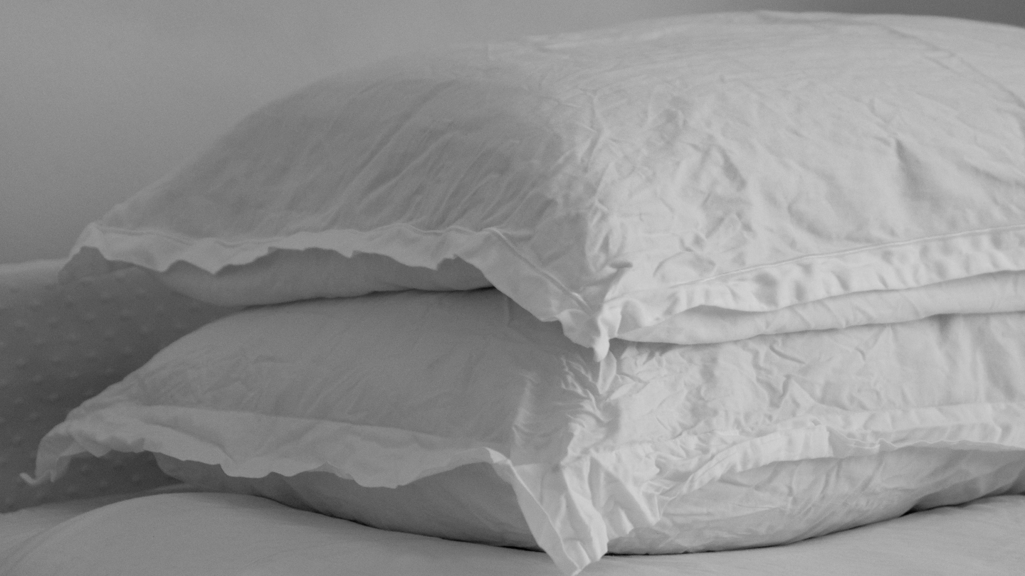 A bed with two pillows on top of each other
