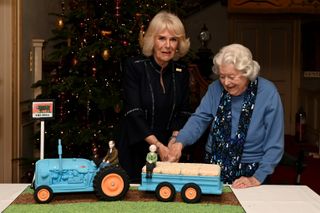 Camilla, Duchess of Cornwall and June Spencer cut an Archers themed cake during a celebration of "The Archers" 70th anniversary