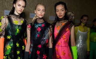 Models wear mesh shirts with fluorescent flower embellishments