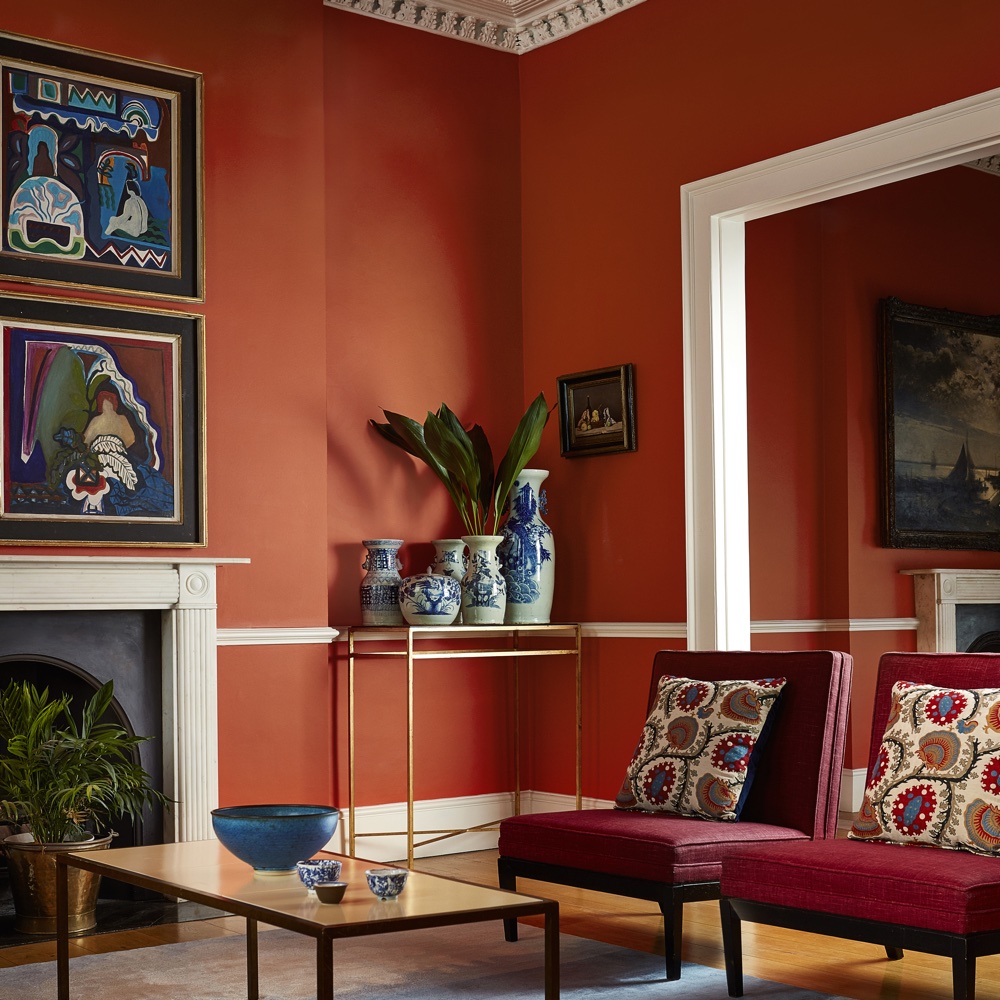 living area with red wall and wooden floor and hairs and vase