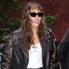 Miley Cyrus wears a white tank top with a miniskirt