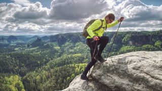 Man backpacker running up on mountain top cliff edge