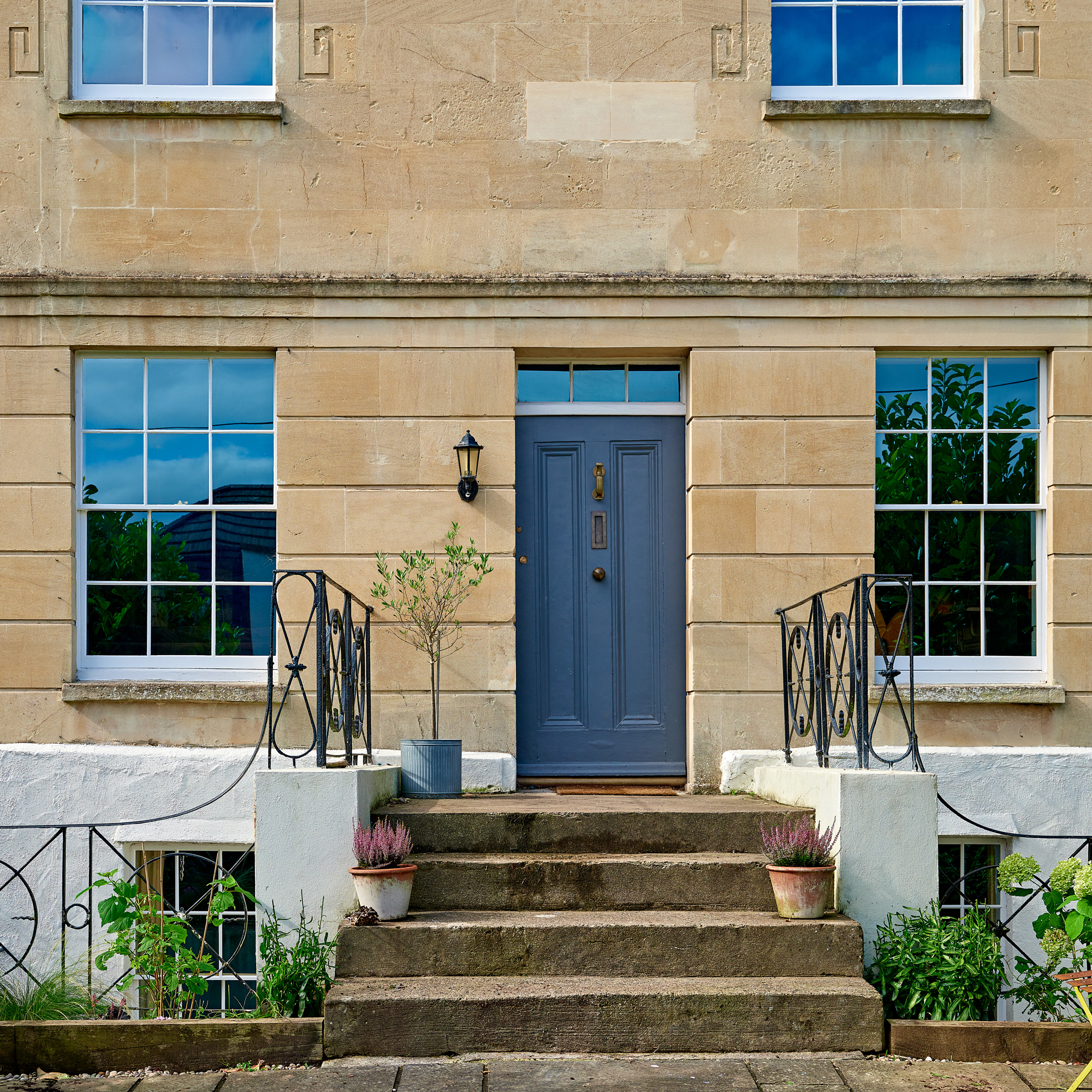 the exterior of a traditional sandstone Georgian house with steps up to the front door