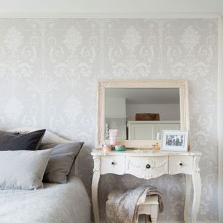 bedroom with grey wallpaper bed with grey cushions and white dressing table