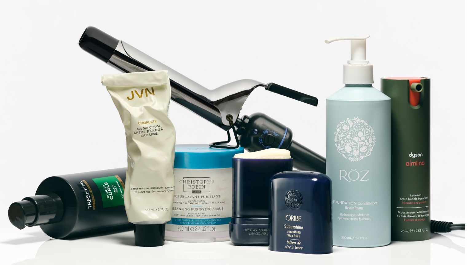 a selection of hair care products and a curling iron on a white background