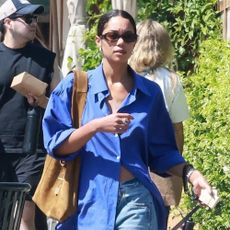 Laura Harrier wears a blue shirt with baggy jeans.