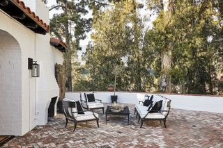 courtyard with tall trees and white walls and garden table near open outdoor fireplace