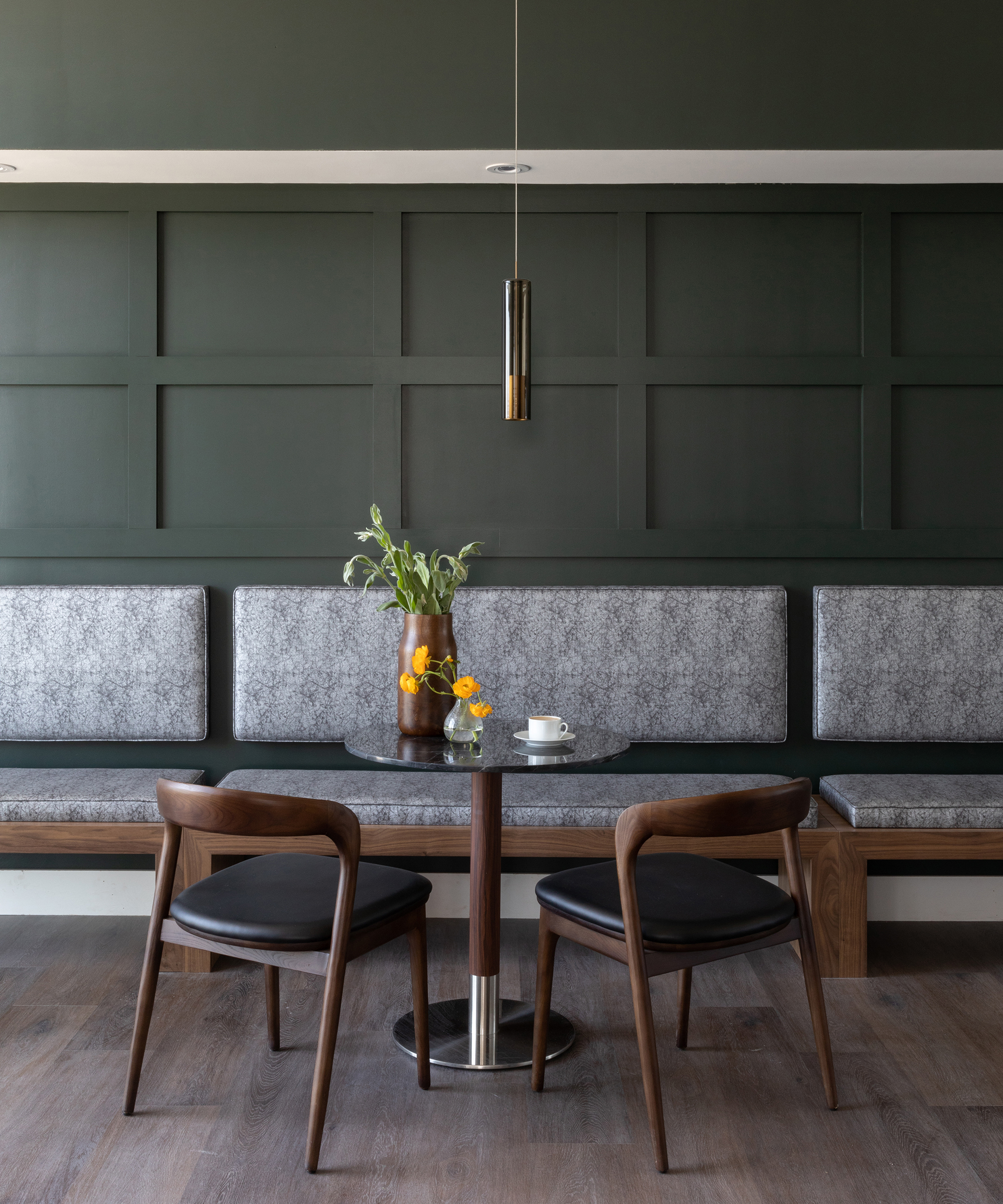 A grey dining room with wall paneling and pendant ceiling