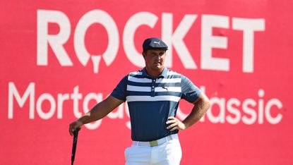 Bryson DeChambeau stands in front of a Rocket Mortgage Classic sign