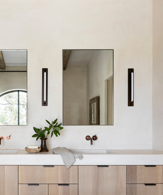 A neutral bathroom with plaster walls and countertops and a large mirror.