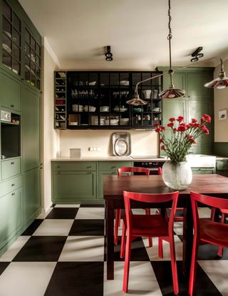 A green kitchen with red chair and carnations